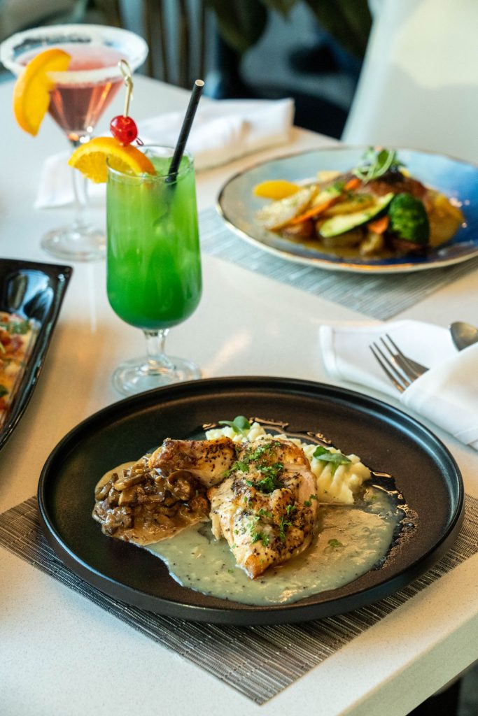 two dinner meals with a green cocktail on a white table cloth