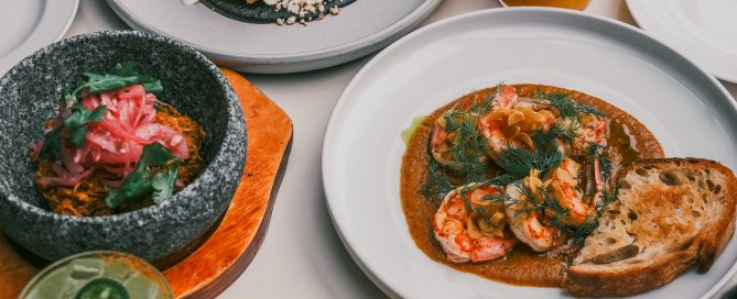 Set table for two at La Taqueria showing two main dishes, a salad, and beverages.