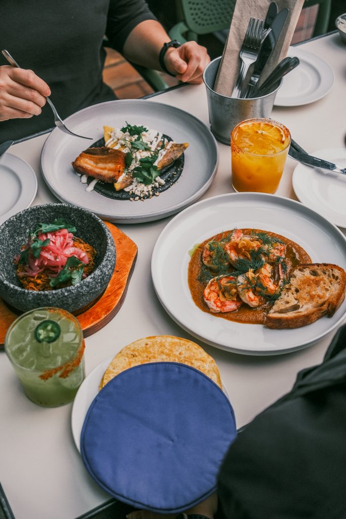 Set table for two at La Taqueria showing two main dishes, a salad, and beverages.