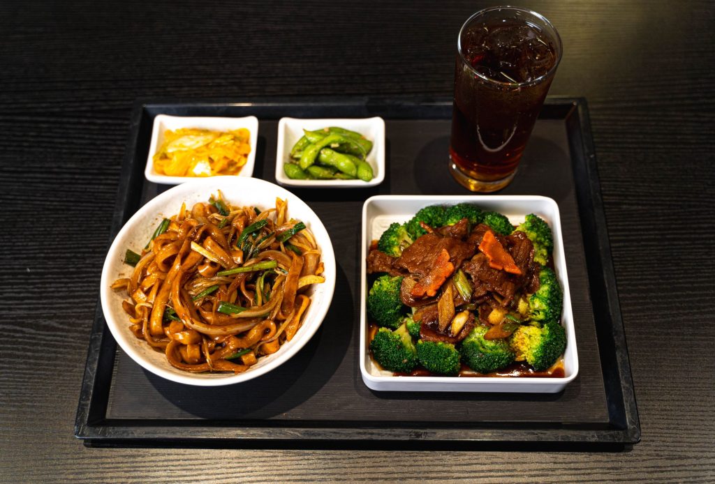 Broccoli beef alongside noodles and side dishes from MYST