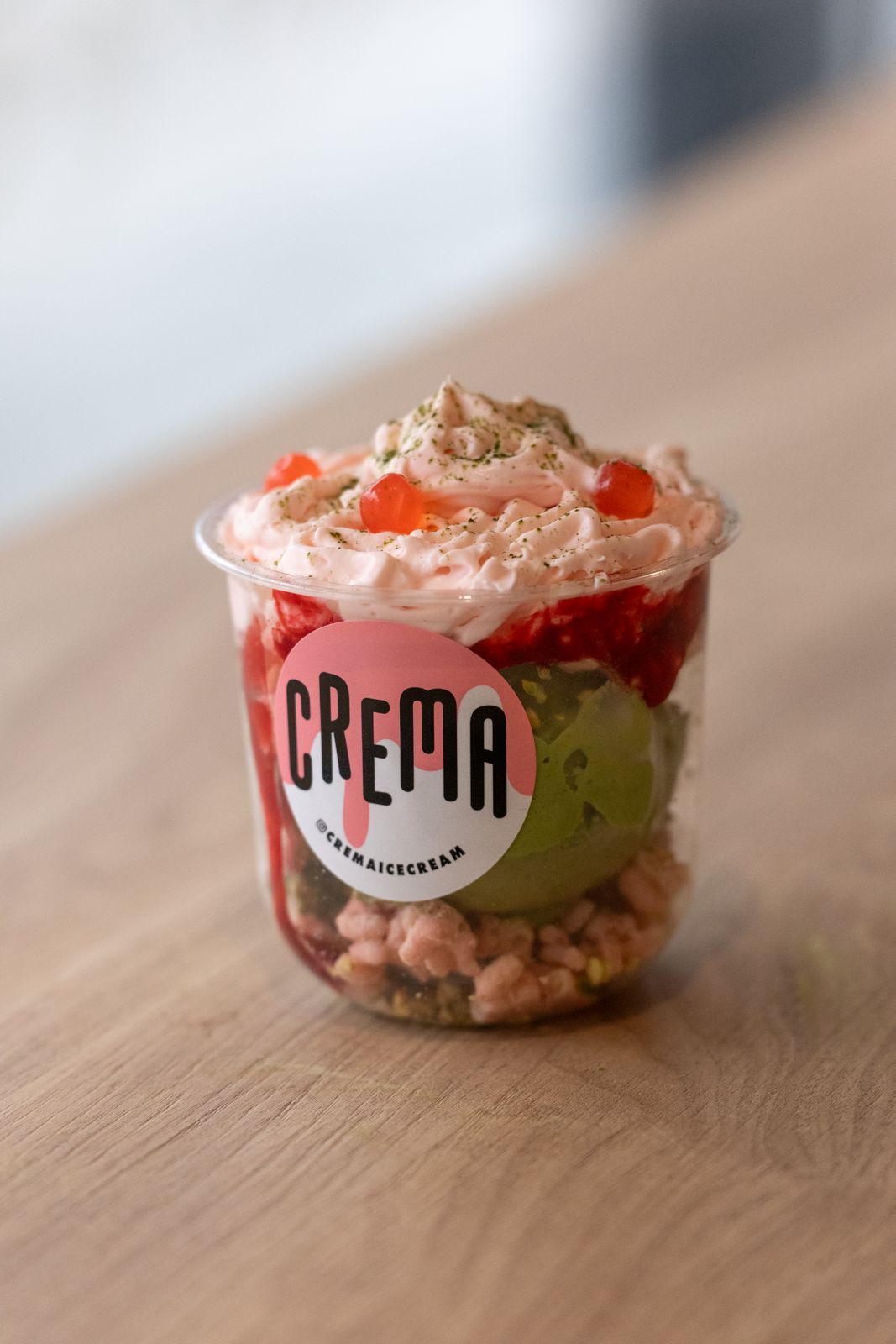 ice cream in clear cup topped with whipped cream and small cherries