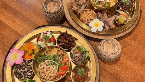 colourful small dishes served on two round wooden trays