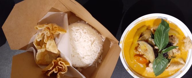 rice and crispy wontons in a to-go box and yellow curry and fresh basil in white to-go box