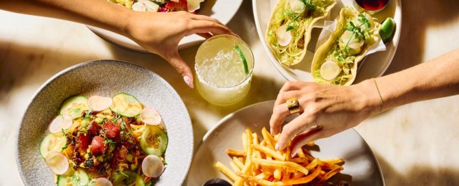 Four round bowls of food displayed on a white plate