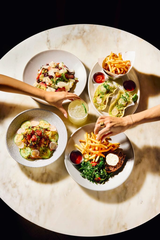 Four round bowls of food displayed on a white plate